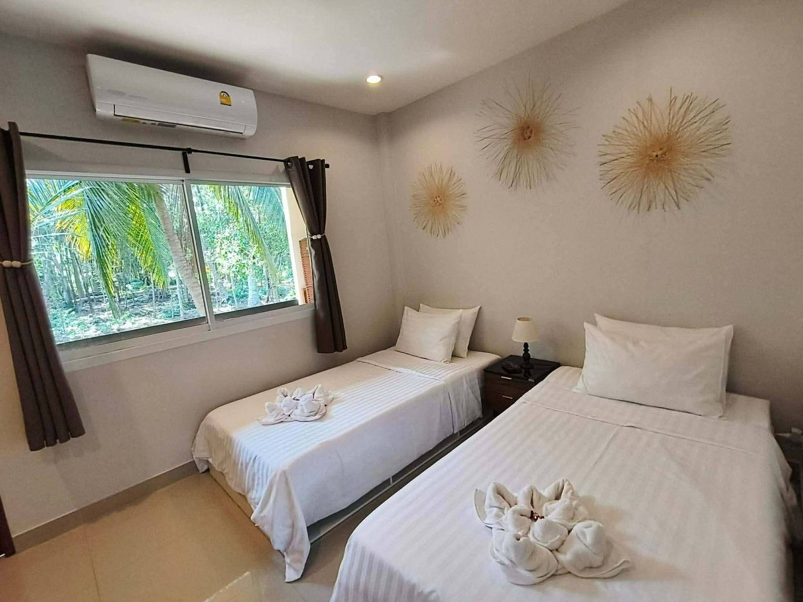 Twin room with two single beds and a window onto coconut palms